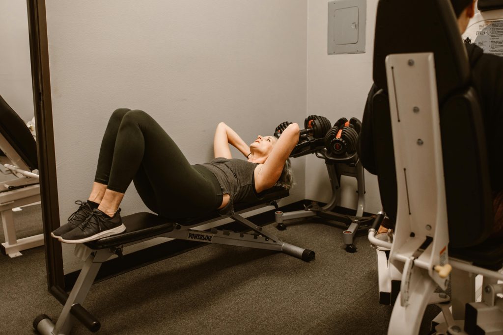 Adult woman exercising on a bench in a gym, promoting fitness and healthy lifestyle.