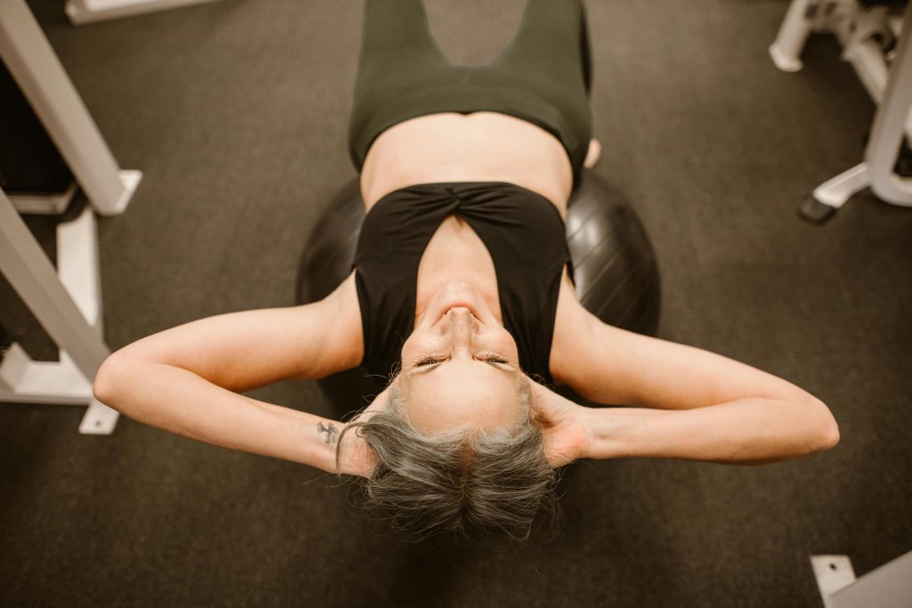 Senior woman performing exercise on stability ball for fitness and strength.